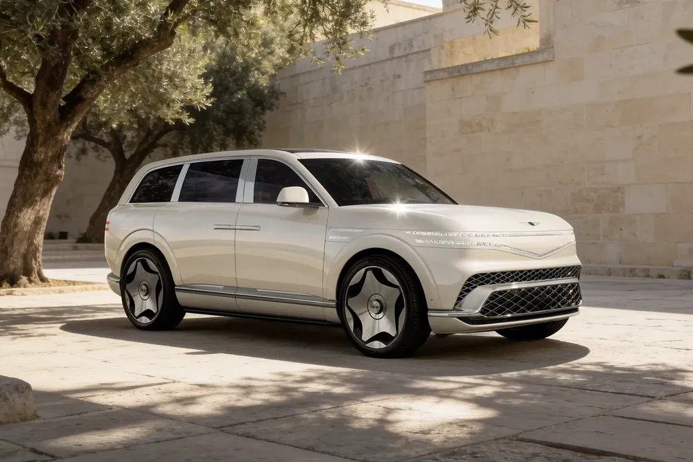Genesis GV80 luxueux SUV blanc garé près d'un mur de pierre et d'arbres.