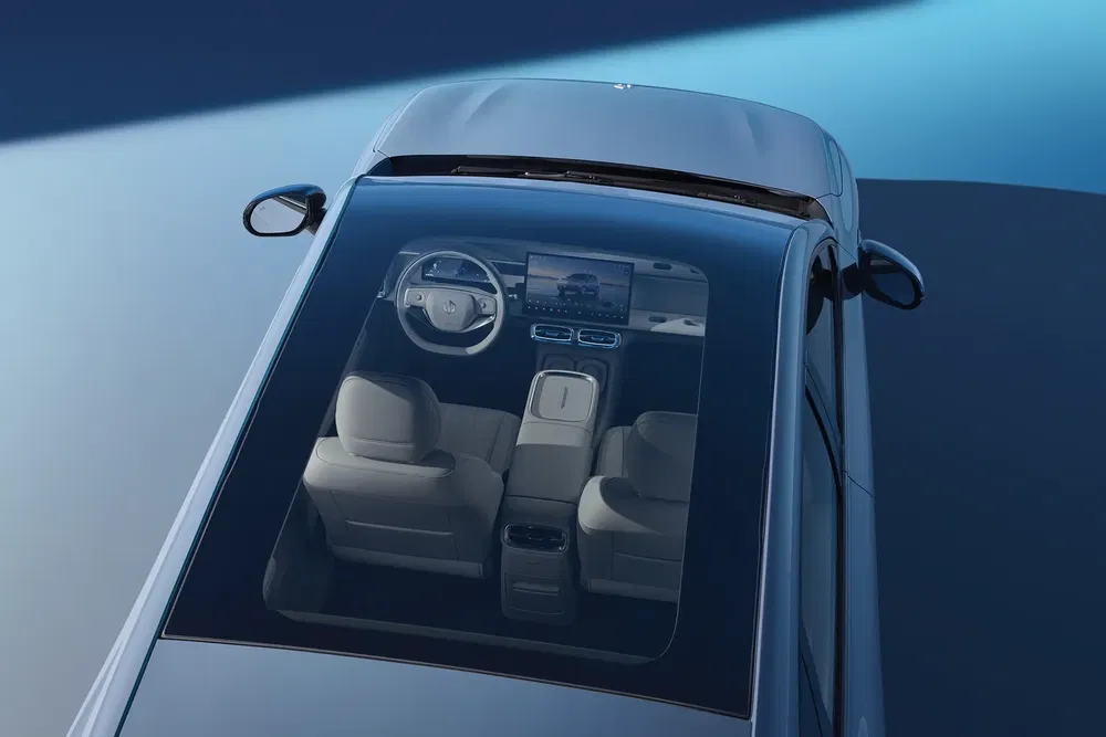 Bovenaanzicht van interieur Mercedes, panoramisch dak, stuur en digitaal scherm zichtbaar.