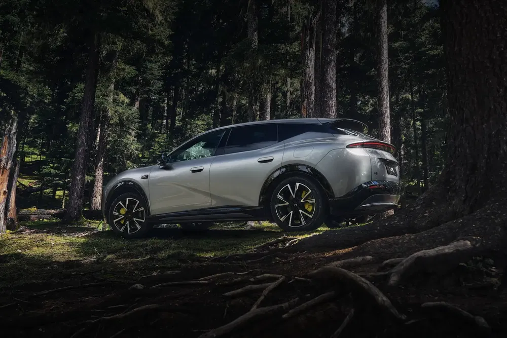 NIO EC7 argenté garé dans une forêt, soulignant son design élégant et moderne.