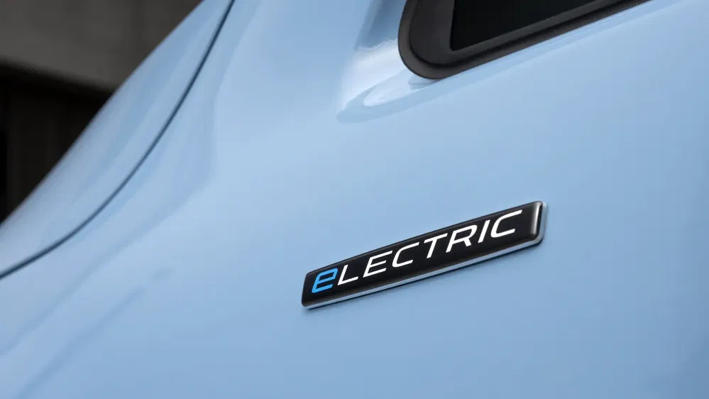 Badge 'Electric' sur carrosserie bleue d'une voiture électrique moderne.