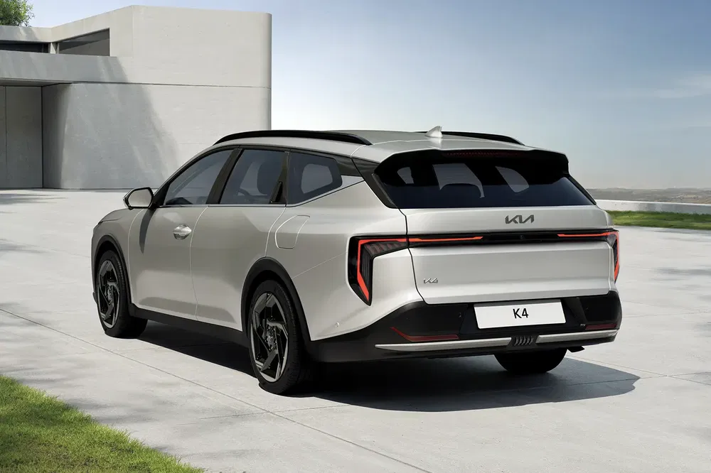 Kia K4 blanc à l'arrière, design moderne devant une maison minimaliste.