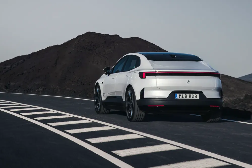 Polestar 2 électrique blanc roulant sur route sinueuse avec montagne en arrière-plan.