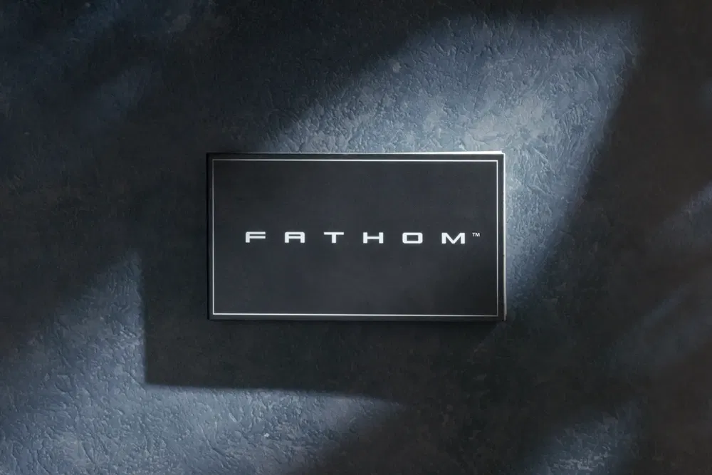 Logo de Fathom sur fond texturé gris avec éclairage dramatique.
