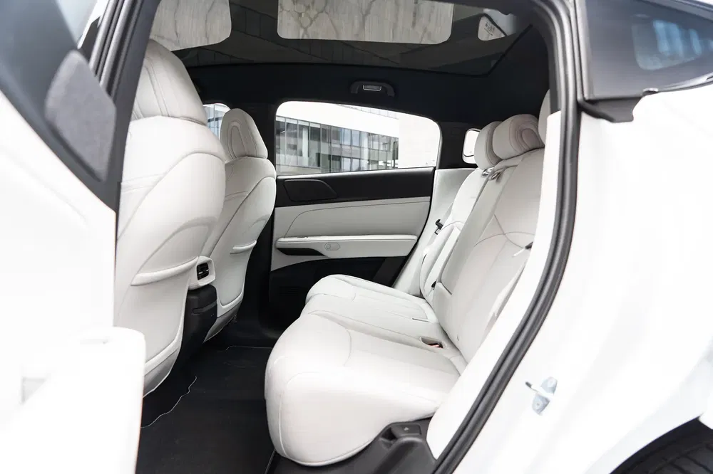 Intérieur spacieux et luxueux de voiture avec sièges arrière en cuir blanc.