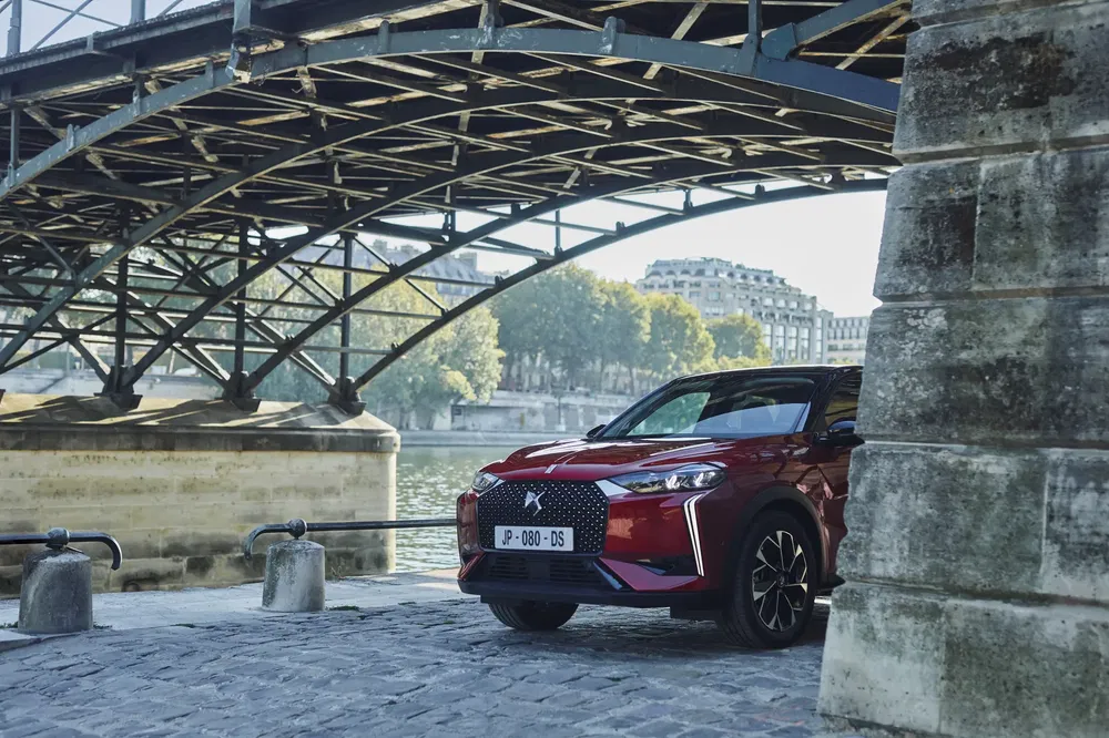 DS 3 Crossback rouge sous un pont parisien au bord de la Seine.