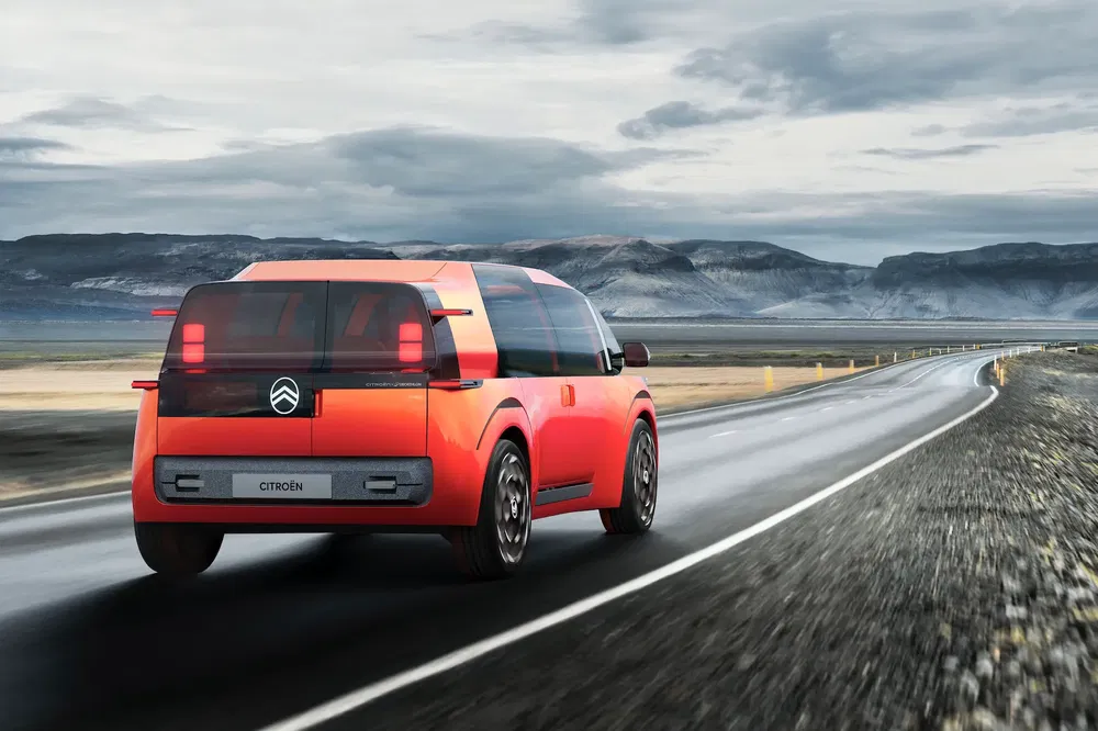 Citroën concept car rouge sur route déserte entourée de montagnes majestueuses.
