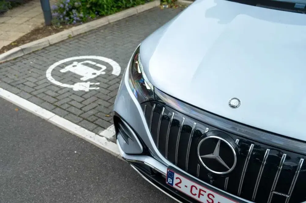 Zilveren Mercedes EQS geparkeerd op een oplaadplaats voor elektrische auto's.