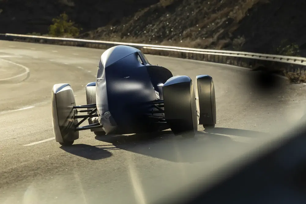 Futuristische auto, bergweg, aerodynamisch ontwerp, scherpe bocht, zonnige rit.