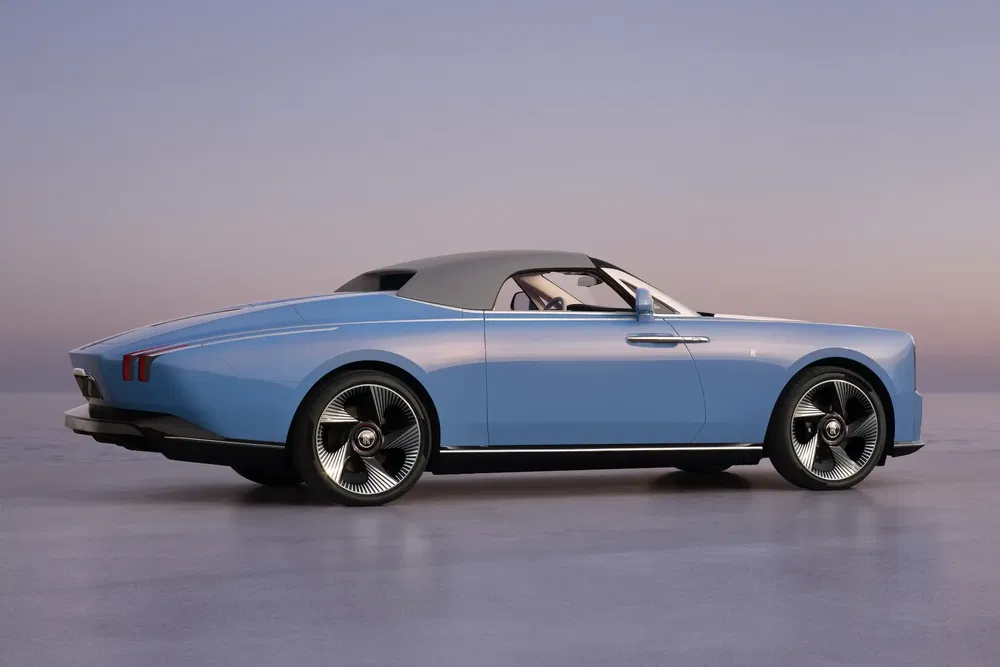 Luxe blauwe auto, grijze kap, chromen velgen, ruime achterkant bij schemering.