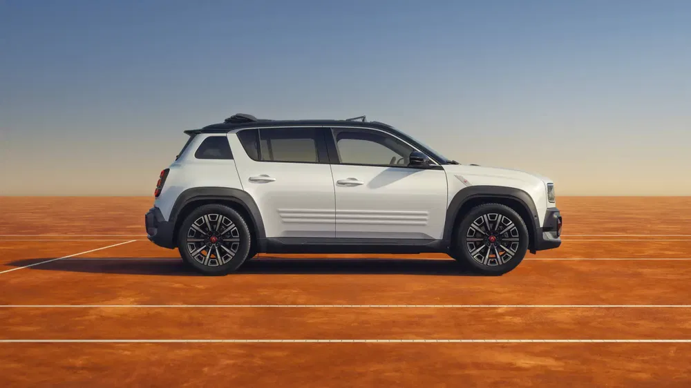 Jeep Renegade blanche garée sur un terrain de sport en terre battue sous un ciel dégagé.