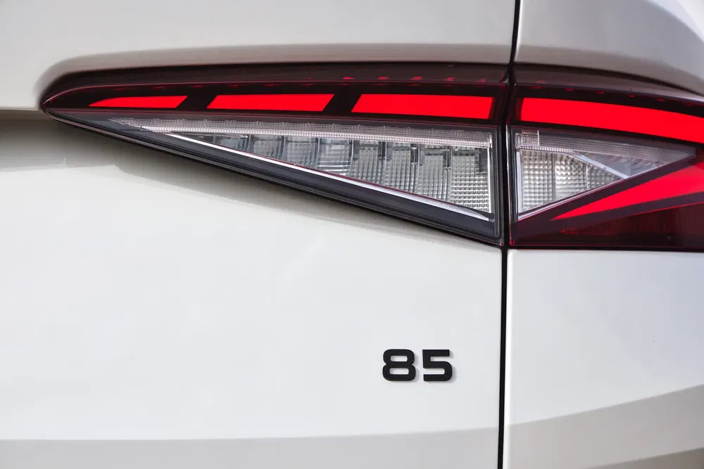 Feu arrière de voiture électrique moderne avec numéro 85 en contraste sur carrosserie blanche.