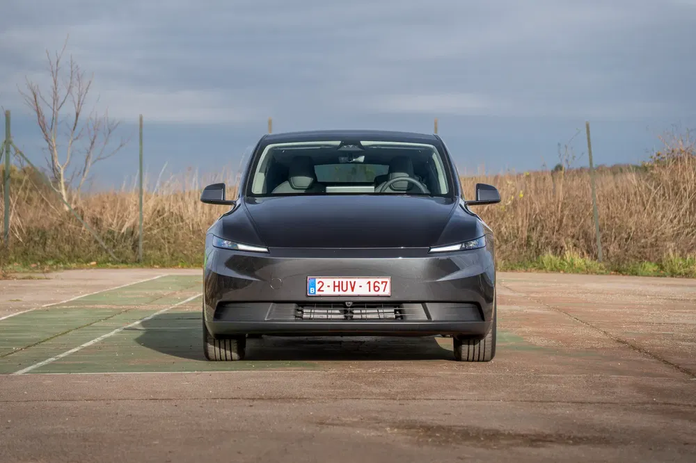 Donkere elektrische auto geparkeerd op verharding, Belgische nummerplaat zichtbaar aan de voorzijde.