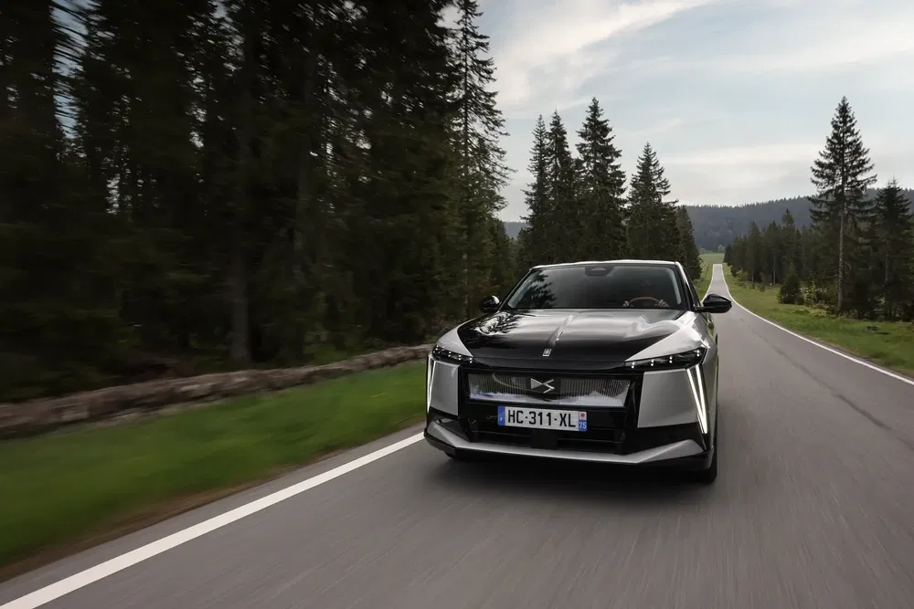 DS 4 rijdt door bosrijke omgeving, elegant en modern ontwerp.