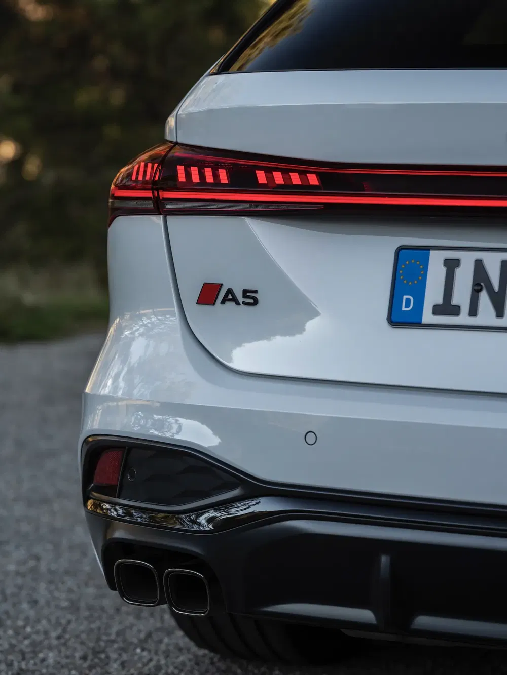 Côté arrière gauche de l'Audi A5 blanche avec phare LED et échappement double.