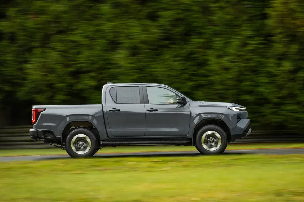 Toyota Hilux 2024 gris roulant sur route avec fond d'arbres.