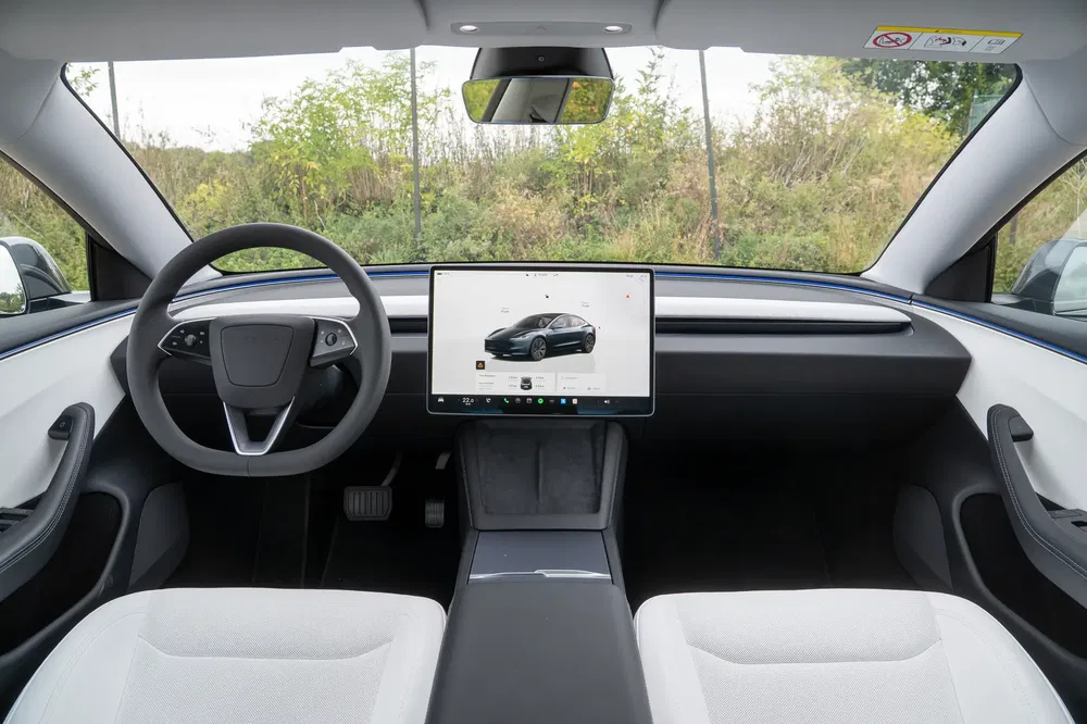 Intérieur moderne de la Tesla Model 3 avec écran tactile central et volant futuriste.