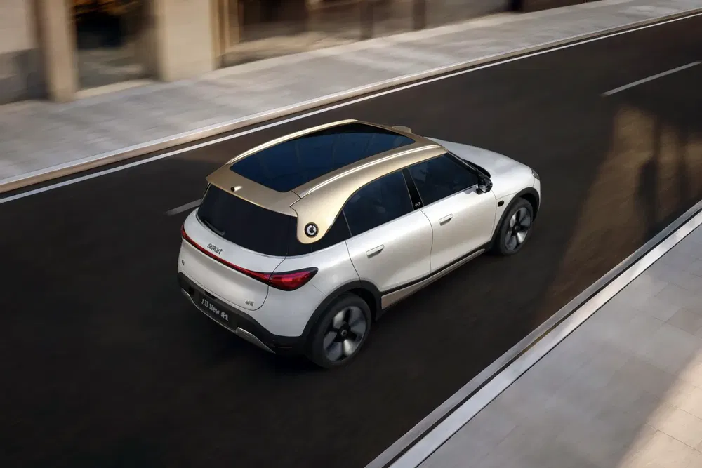 SUV Smart #1 châssis argenté sur route urbaine, toit panoramique impressionnant.