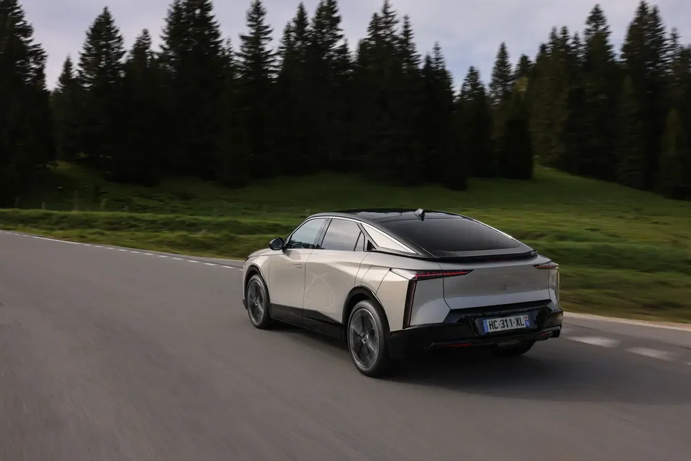 Elektrische auto rijdt door bosrijk gebied op kronkelige weg.