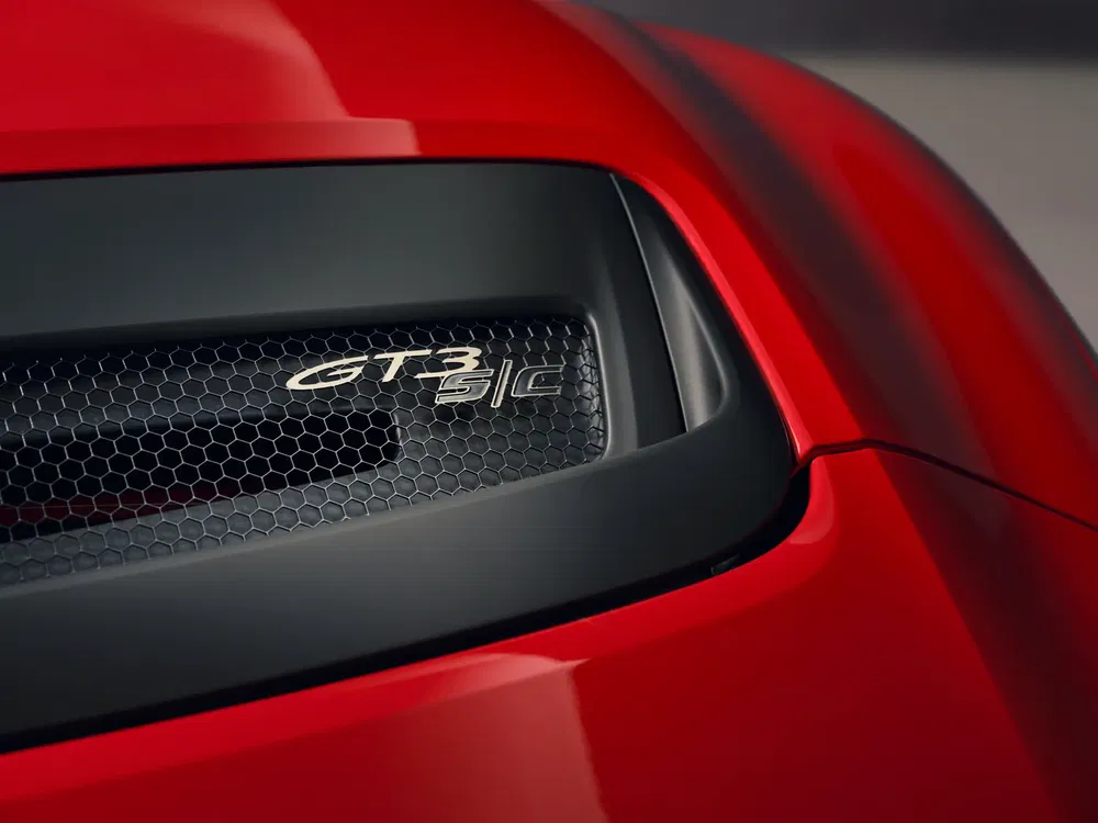 Détail de l'aération arrière d'une Porsche GT3 RS rouge, logo visible sur la calandre.