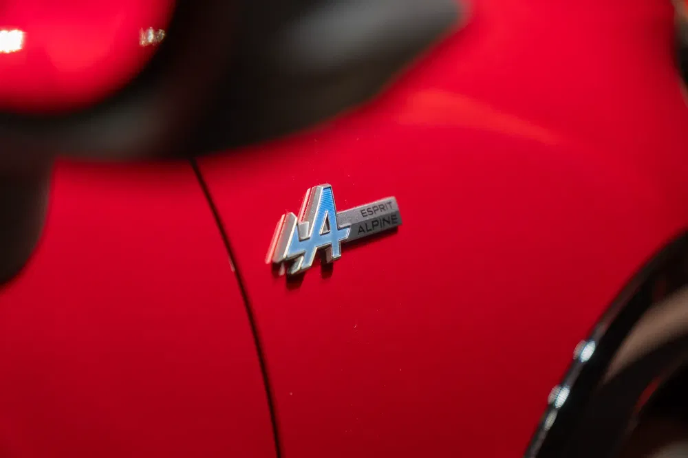 Alpine Esprit logo op rode carrosserie van een sportwagen.