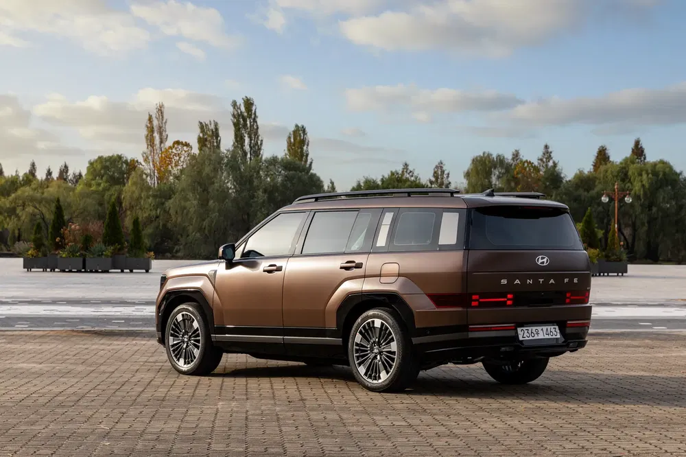 Bruine Hyundai Santa Fe SUV op geplaveid plein met bomen op de achtergrond.