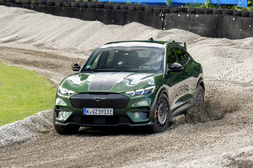 Groene Ford Mustang Mach-E drift op een grindcircuit.