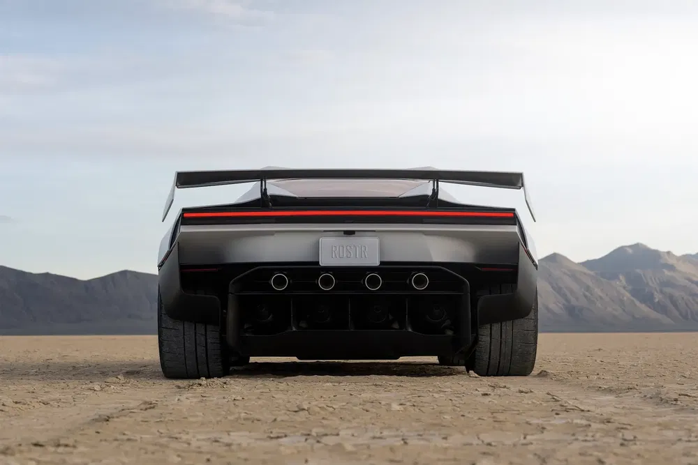 Vue arrière d'une voiture de sport moderne sur un désert, avec aileron et quadruple échappement.