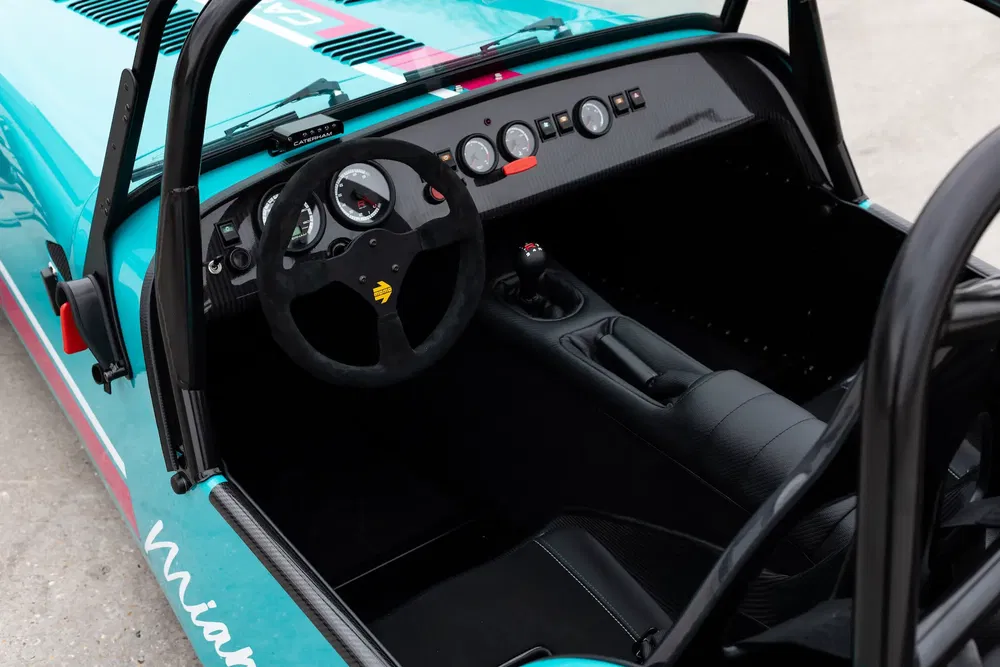 {"fr":"Intérieur d'une Caterham Roadsport avec tableau de bord analogique et volant sport.","nl":"Interieur van een Caterham Roadsport met analoog dashboard en sportstuur."}