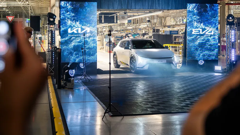 {"fr":"Kia EV9 électrique en sortie d'usine avec éclairage de scène et écrans LED.","nl":"Kia EV9 elektrisch voertuig verlaat fabriek met podiumverlichting en LED-schermen."}