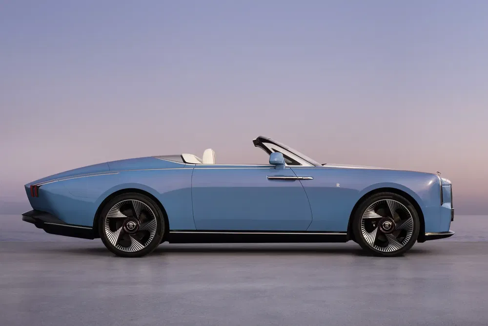 Blauwe Rolls-Royce cabriolet met luxe design tegen een schemerige hemel achtergrond.