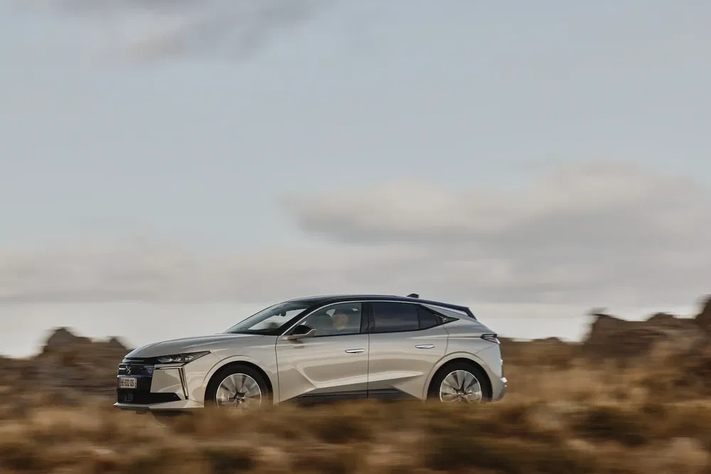 Vue latérale de la Citroën C5 X grise, roulant dans un paysage naturel.