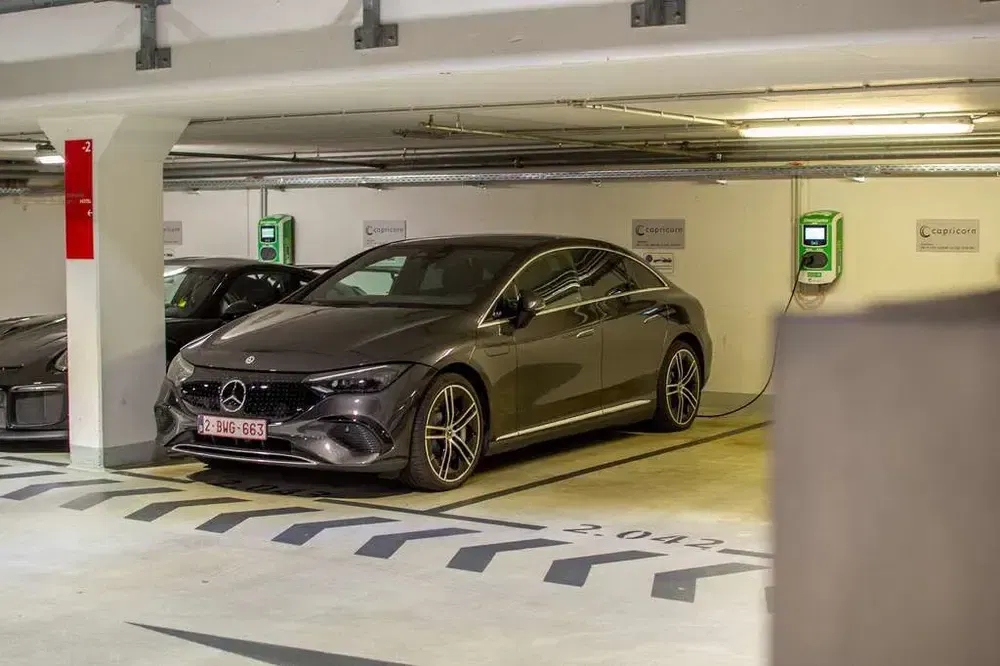 Donkergrijze elektrische Mercedes aan het opladen in een moderne parkeergarage.