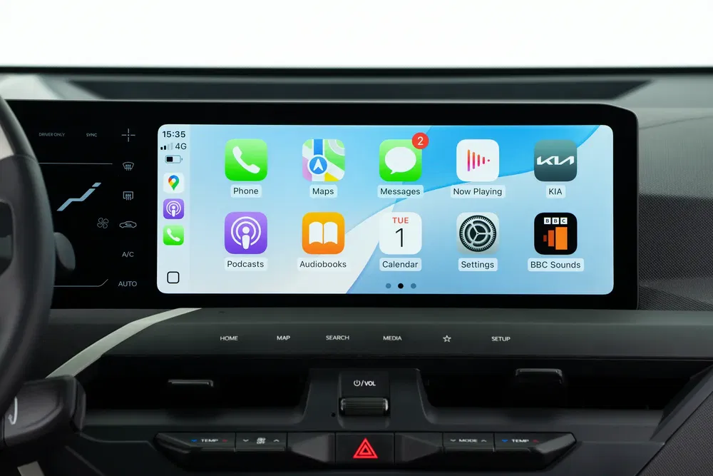 Kia autoradio-touchscreen toont Apple CarPlay met diverse app-iconen.