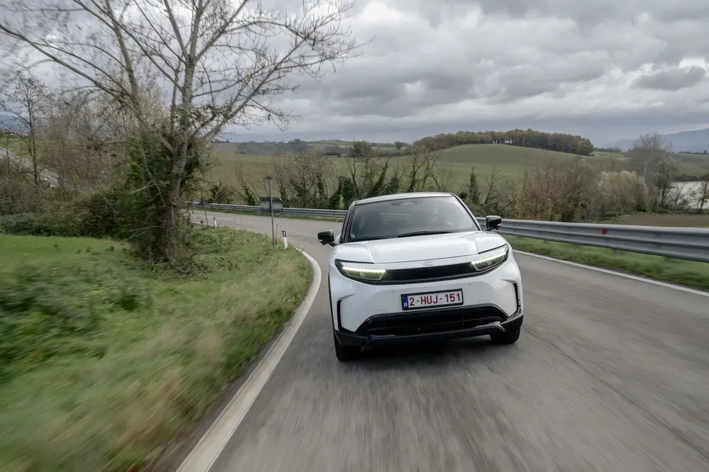 Voiture électrique blanche Geely Zeekr X roulant sur une route de campagne sinueuse.