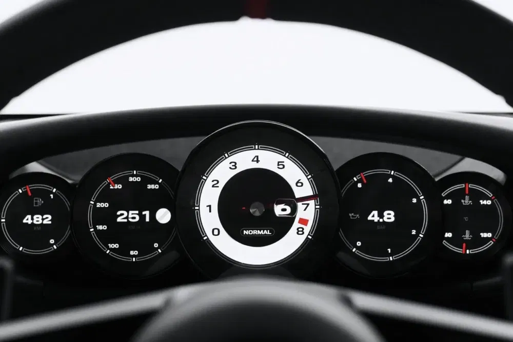 Dashboard Porsche met digitale snelheidsmeter en verlichte meters.