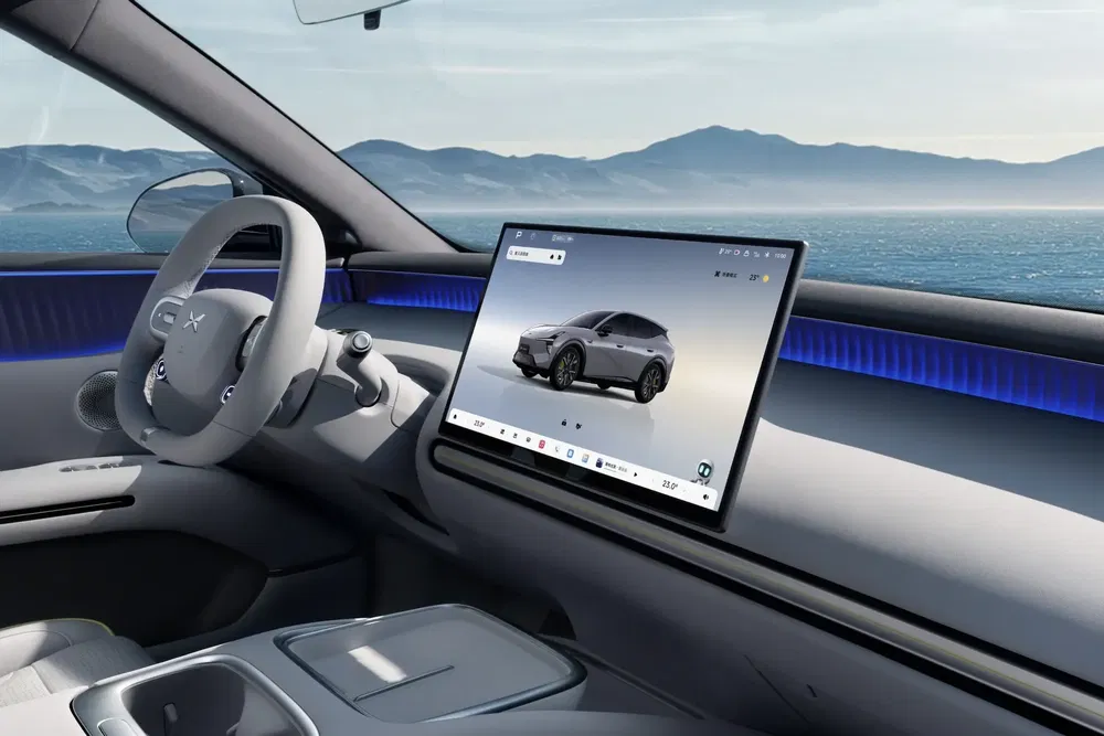 Intérieur moderne d'une voiture électrique XPeng avec écran tactile large, vue mer en arrière-plan.