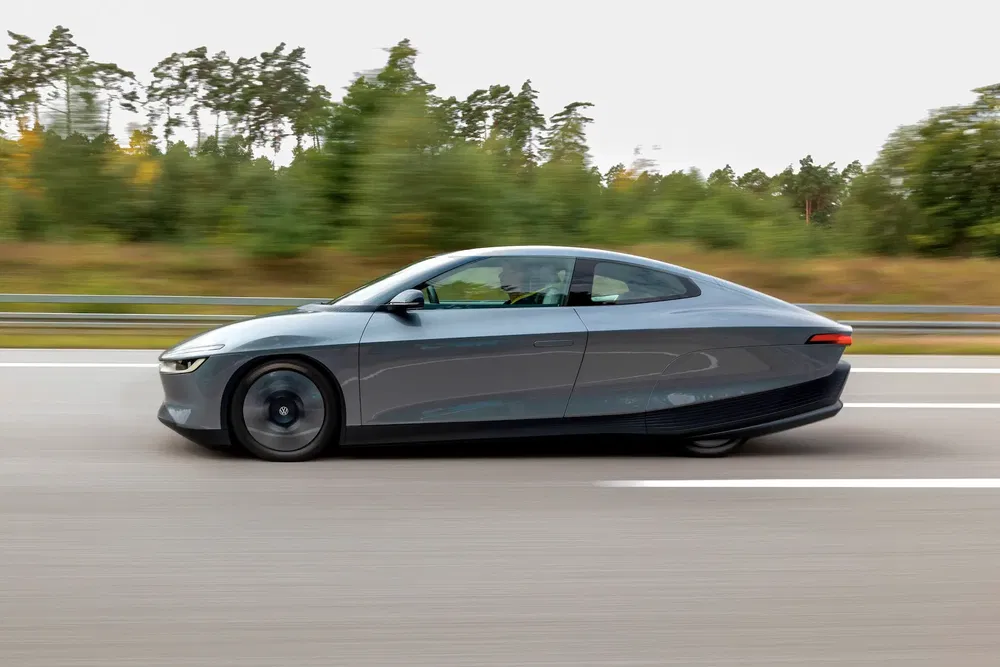 Voiture électrique Lightyear Zero roulant à grande vitesse sur une autoroute boisée.