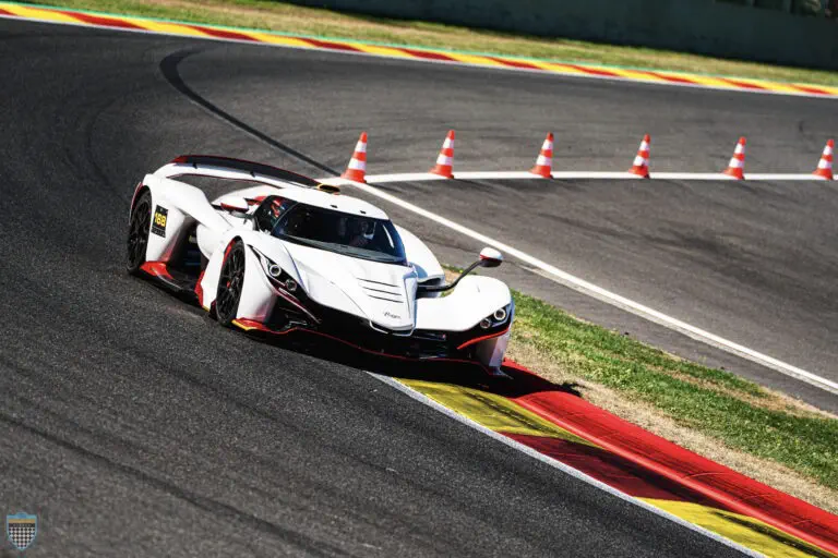 Witte Apollo IE hypercar op racecircuit, scherpe bocht met verkeerskegels.