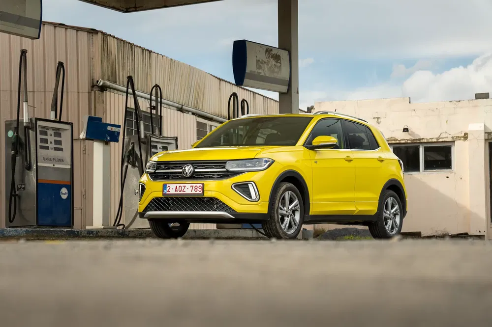 Gele Volkswagen T-Cross geparkeerd bij een verlaten benzinestation.
