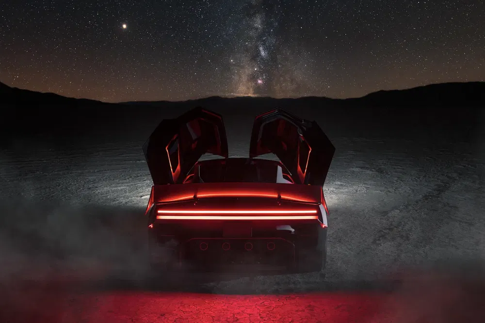 Voiture de sport futuriste sous ciel nocturne étoilé avec portes en élytre ouvertes.