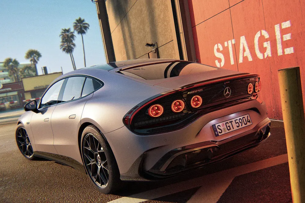Grijze Mercedes AMG GT geparkeerd voor rode muur, palmbomen op de achtergrond.