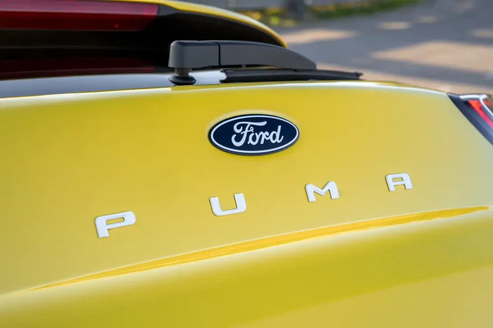 Logo Ford Puma sur hayon jaune éclatant sous la lumière du jour.