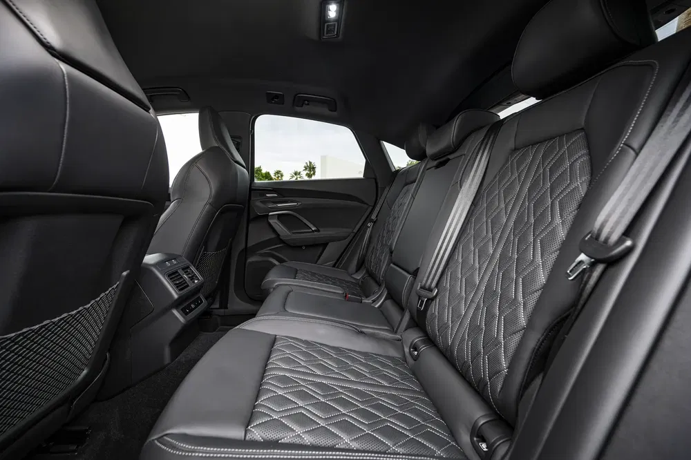 Intérieur luxueux Audi, sièges arrière en cuir noir matelassé, espace spacieux et confort premium.