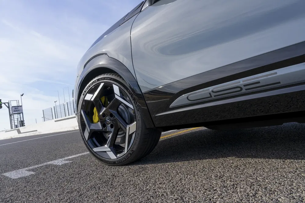 Zijaanzicht van een Opel auto met lichtmetalen velgen en GSe logo op circuit.