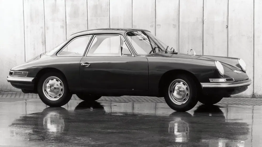 Ancienne Porsche 911 noire, design classique, stationnée devant un mur en béton.
