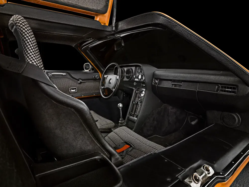 Intérieur de voiture vintage avec sièges à motif pied-de-poule et volant sportif.