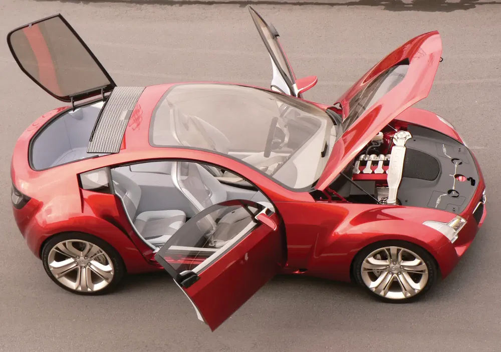 Voiture concept rouge avec portes papillon et toit transparent, capot et portes ouvertes.