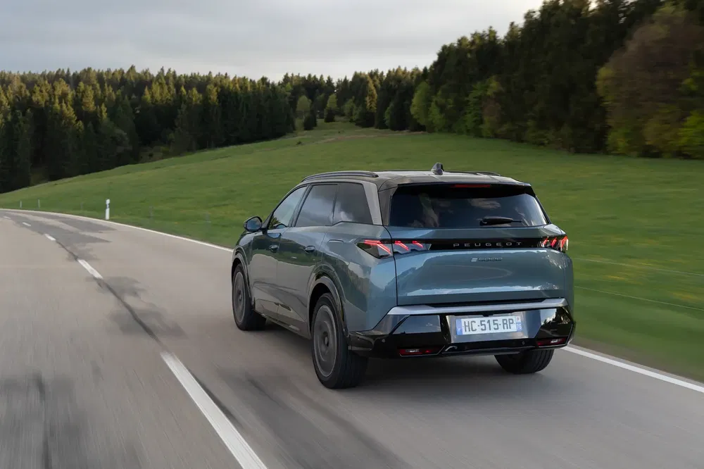 Peugeot 3008 rijdt op een landelijke weg omgeven door groene bossen.