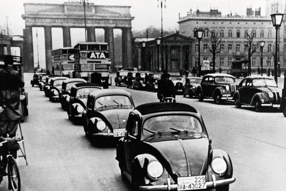 Voitures Volkswagen Coccinelle devant la Porte de Brandebourg dans les années 1960, Berlin.