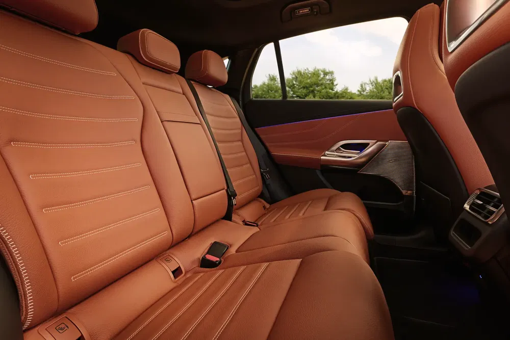 Ruime auto-interieur met bruine lederen stoelen en luxe afwerking.